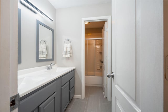 bathroom featuring tile patterned flooring, vanity, and combined bath / shower with glass door