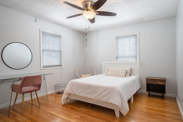 bedroom with a textured ceiling, light hardwood / wood-style floors, and ceiling fan