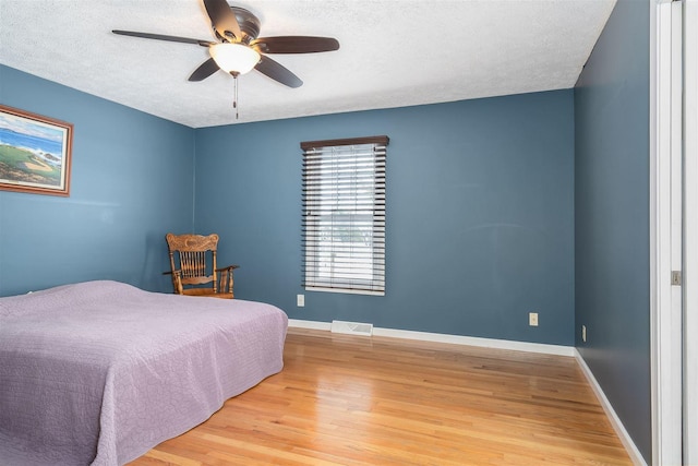 bedroom featuring a textured ceiling, light hardwood / wood-style floors, and ceiling fan