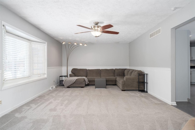 carpeted living room with ceiling fan and a textured ceiling