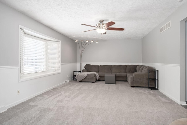 living room featuring light carpet, ceiling fan, and a textured ceiling