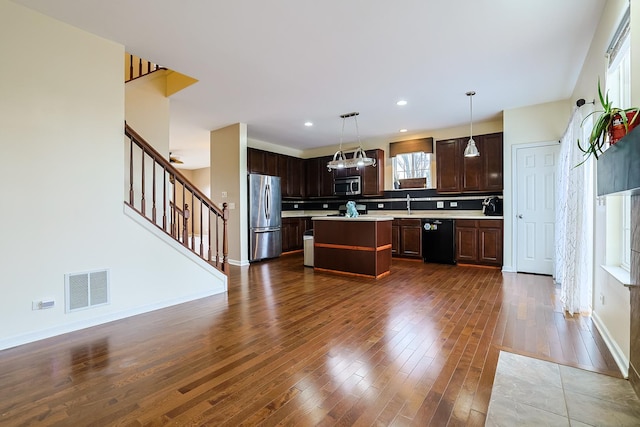 kitchen featuring pendant lighting, a kitchen island, dark hardwood / wood-style flooring, dark brown cabinetry, and stainless steel appliances