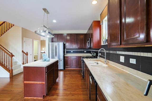 kitchen featuring pendant lighting, sink, dark hardwood / wood-style floors, a kitchen island, and stainless steel appliances