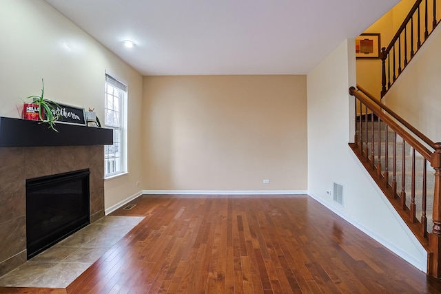 unfurnished living room with a tile fireplace and hardwood / wood-style floors