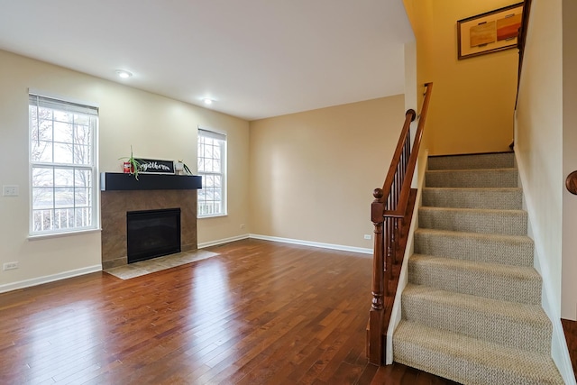 unfurnished living room featuring a tile fireplace and hardwood / wood-style flooring