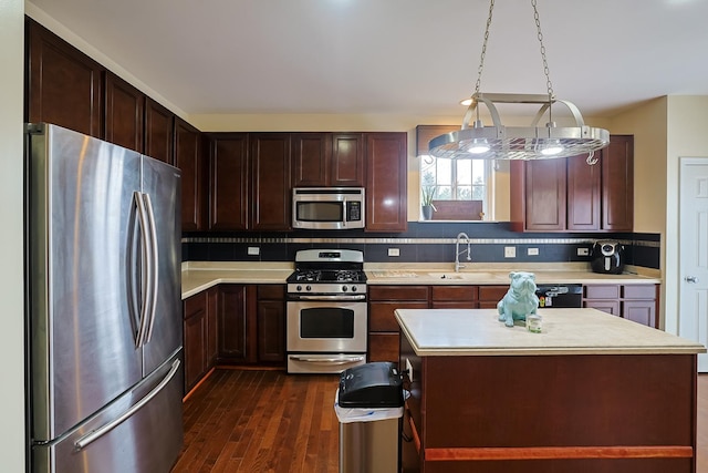 kitchen featuring backsplash, stainless steel appliances, sink, a kitchen island, and hanging light fixtures