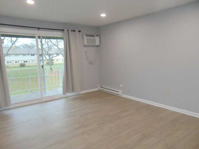 spare room featuring a wall mounted AC, light hardwood / wood-style floors, and baseboard heating