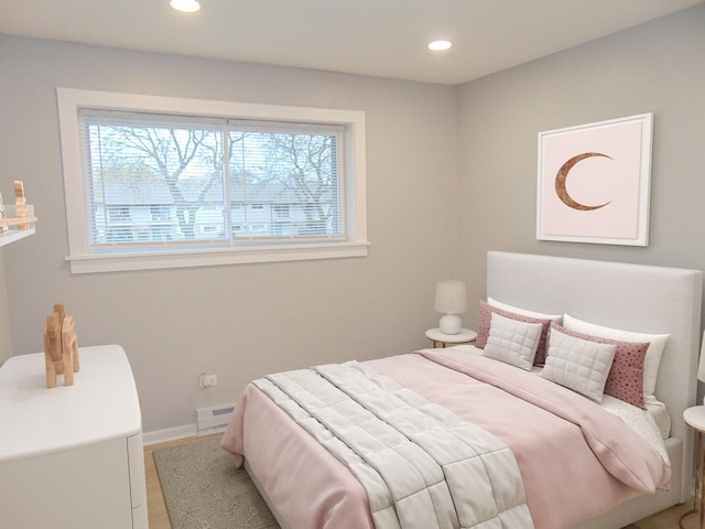 bedroom featuring multiple windows, hardwood / wood-style flooring, and a baseboard heating unit