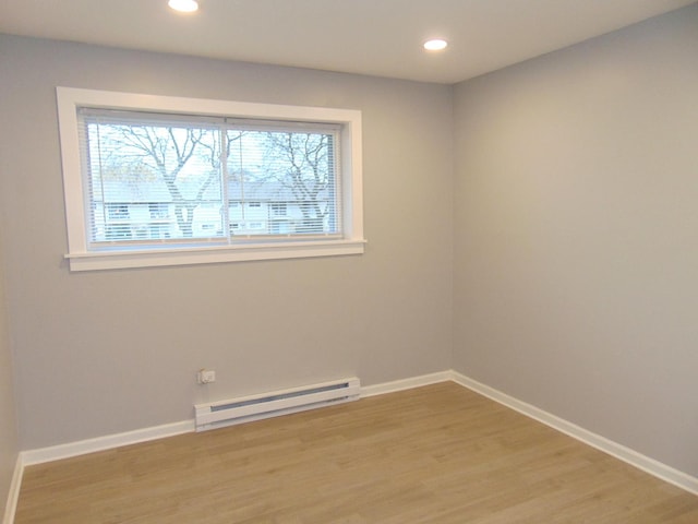 unfurnished room featuring light hardwood / wood-style floors, baseboard heating, and a wealth of natural light