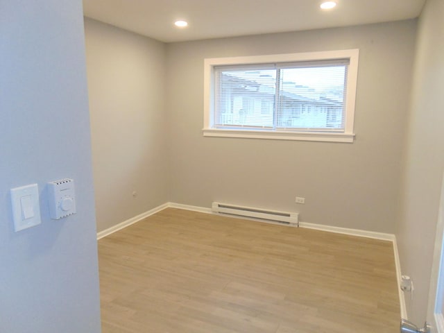 empty room with baseboard heating and light hardwood / wood-style flooring