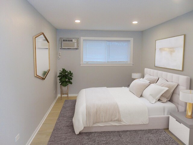 bedroom with light wood-type flooring and a wall unit AC