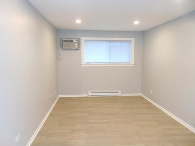 empty room featuring a baseboard radiator, a wall mounted air conditioner, and light hardwood / wood-style floors