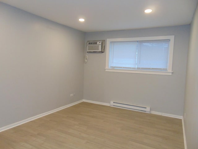 spare room with light wood-type flooring, a baseboard radiator, and an AC wall unit