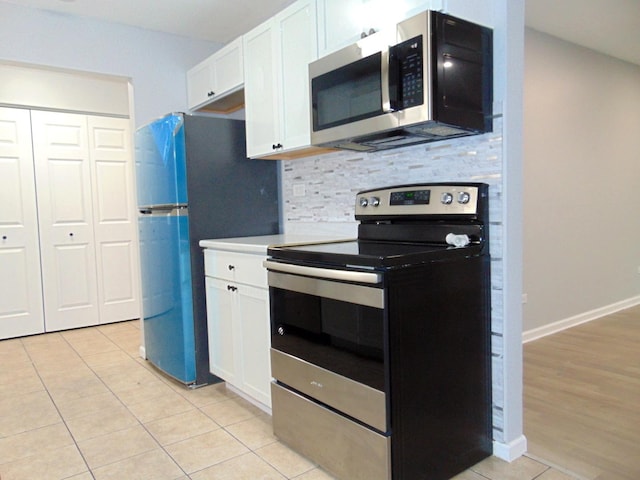 kitchen with white cabinets, appliances with stainless steel finishes, backsplash, and light tile patterned floors