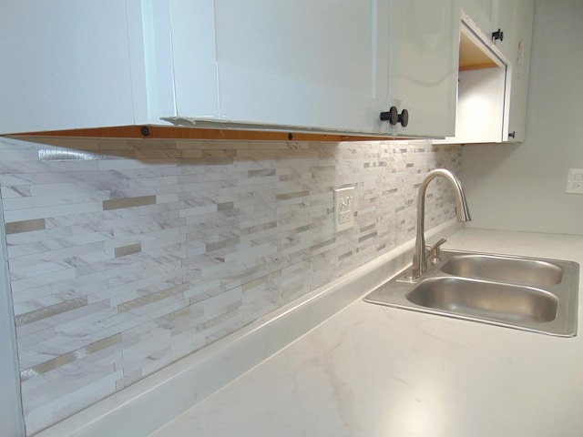 room details featuring tasteful backsplash, white cabinetry, and sink