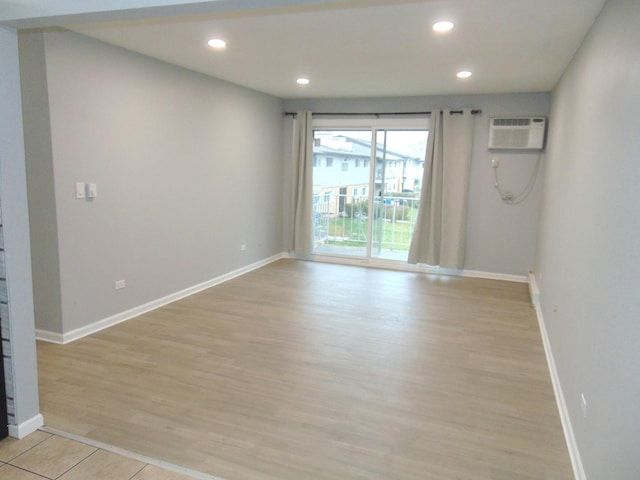 unfurnished room featuring light wood-type flooring and an AC wall unit