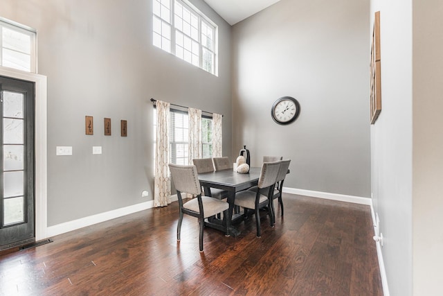 dining area featuring dark hardwood / wood-style flooring and a high ceiling