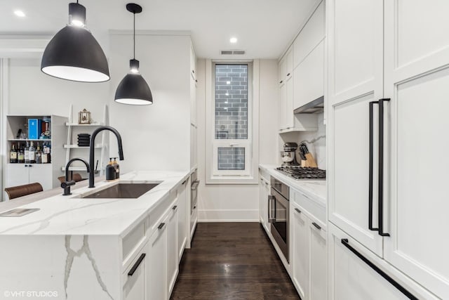 kitchen with light stone countertops, stainless steel gas cooktop, sink, pendant lighting, and white cabinets