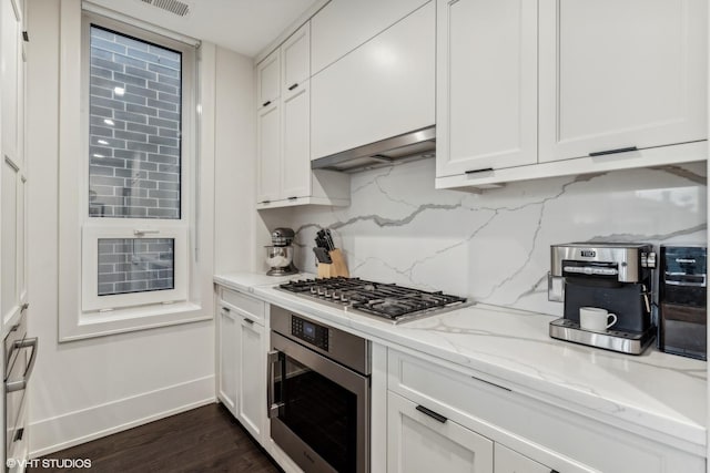 kitchen with decorative backsplash, wall oven, light stone counters, dark wood-type flooring, and white cabinets