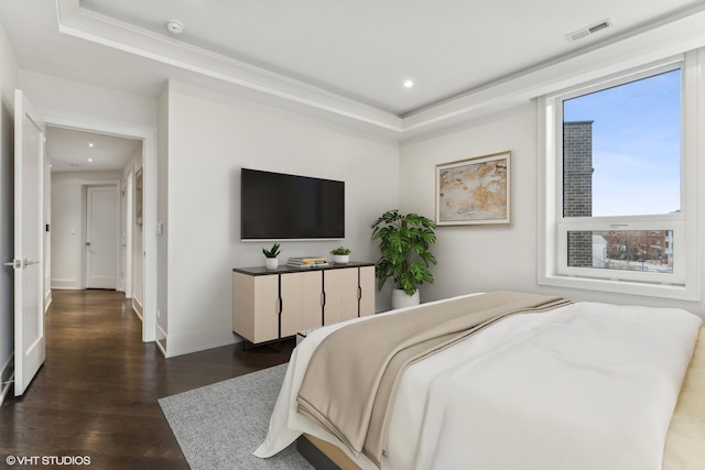 bedroom with a tray ceiling, crown molding, and dark wood-type flooring