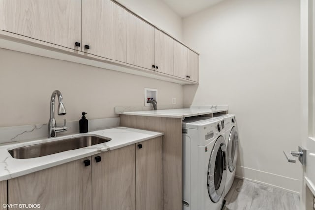 laundry area with washer and dryer, sink, cabinets, and light hardwood / wood-style flooring