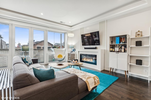 living room with a tray ceiling and dark hardwood / wood-style flooring