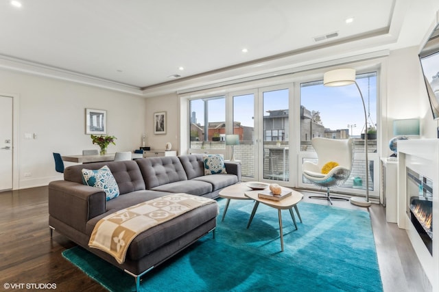 living room with hardwood / wood-style floors, a healthy amount of sunlight, and a tray ceiling