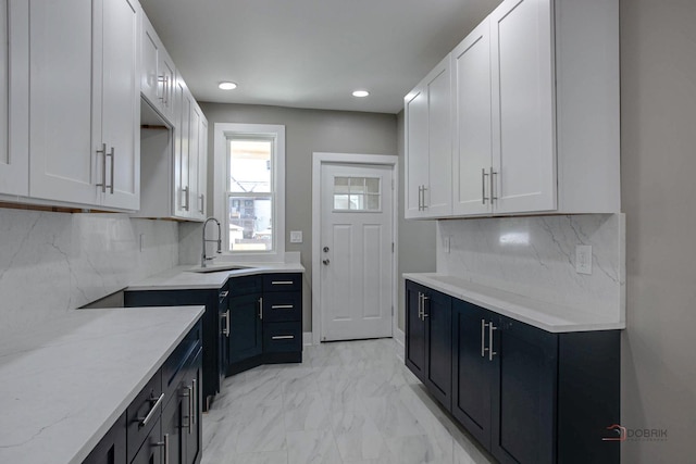 kitchen featuring sink, white cabinetry, and light stone counters