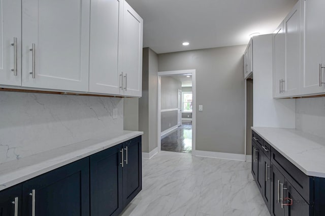 kitchen with backsplash, white cabinetry, and light stone counters