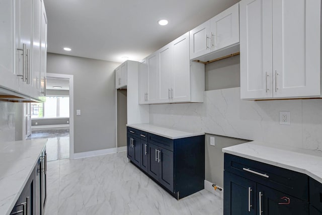 kitchen featuring tasteful backsplash, white cabinetry, and light stone counters