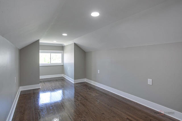 additional living space with vaulted ceiling and dark wood-type flooring