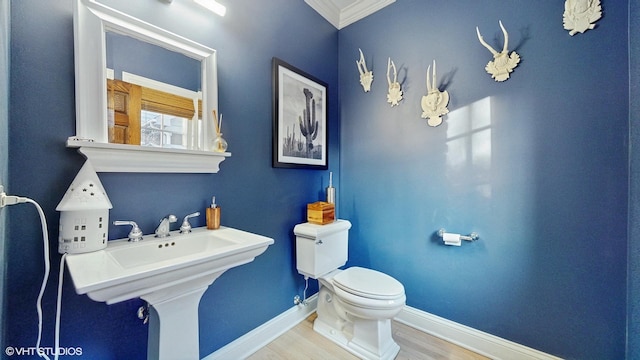 bathroom with wood-type flooring, toilet, and crown molding