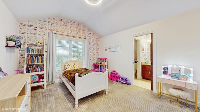 carpeted bedroom with ensuite bathroom and vaulted ceiling