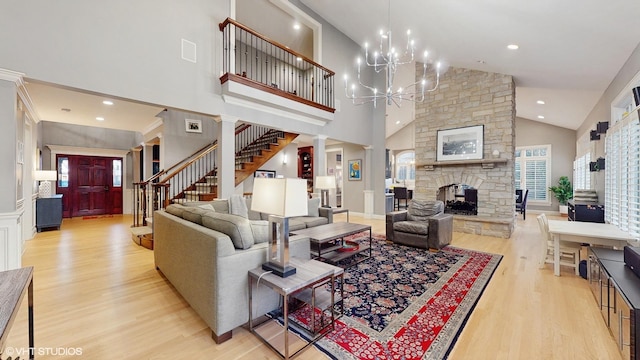 living room featuring decorative columns, a fireplace, high vaulted ceiling, and light hardwood / wood-style flooring