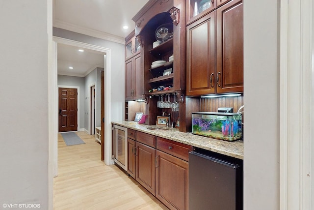 bar featuring wine cooler, light stone counters, ornamental molding, fridge, and light wood-type flooring