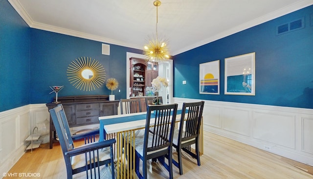 dining area with ornamental molding, light wood-type flooring, and a notable chandelier