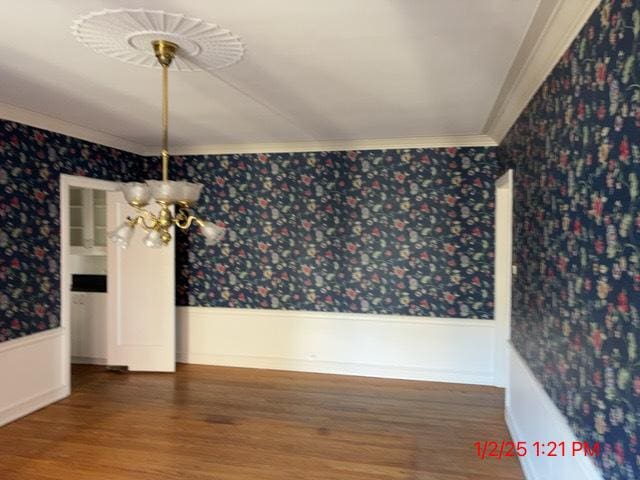 unfurnished dining area with ornamental molding, hardwood / wood-style flooring, and a notable chandelier