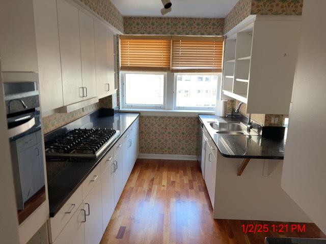 kitchen with sink, white cabinetry, light hardwood / wood-style floors, kitchen peninsula, and appliances with stainless steel finishes