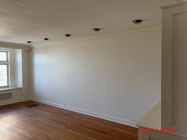 empty room featuring dark hardwood / wood-style flooring and ornamental molding