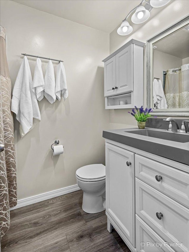 bathroom with toilet, hardwood / wood-style flooring, and vanity