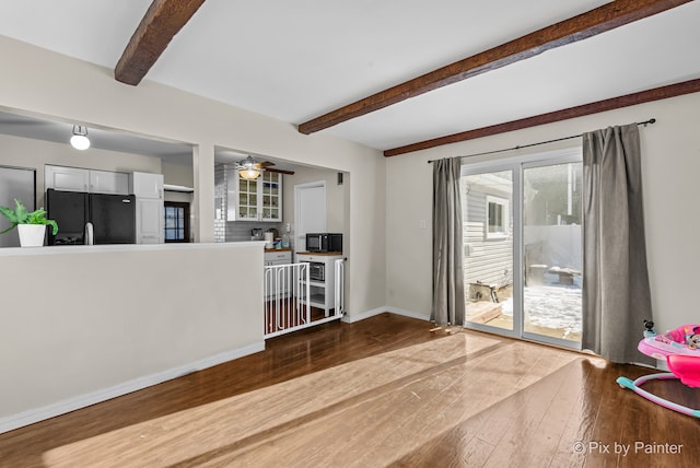 living room featuring ceiling fan, hardwood / wood-style floors, and beamed ceiling