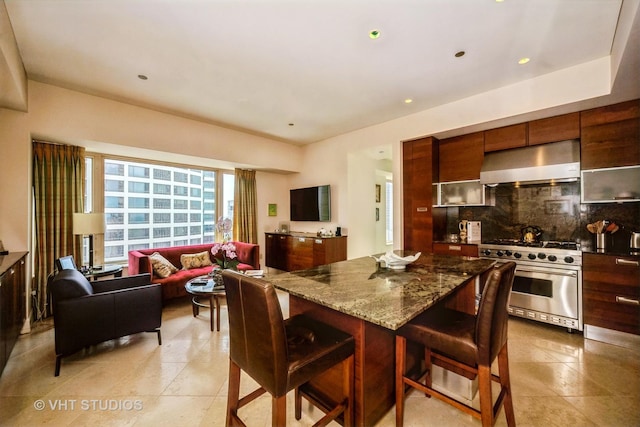 kitchen featuring a breakfast bar area, high end range, tasteful backsplash, stone countertops, and exhaust hood