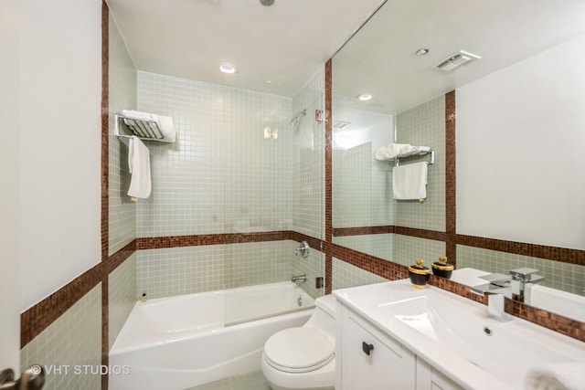 full bathroom with vanity, tiled shower / bath, tile walls, and toilet