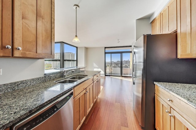 kitchen featuring sink, hanging light fixtures, dark wood-type flooring, dark stone countertops, and appliances with stainless steel finishes