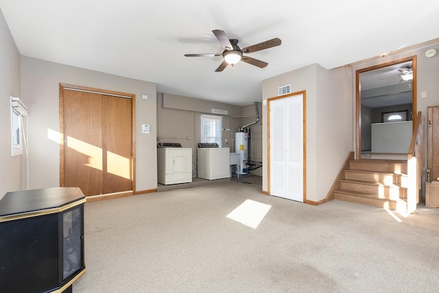 unfurnished living room featuring ceiling fan, light colored carpet, gas water heater, and washing machine and clothes dryer