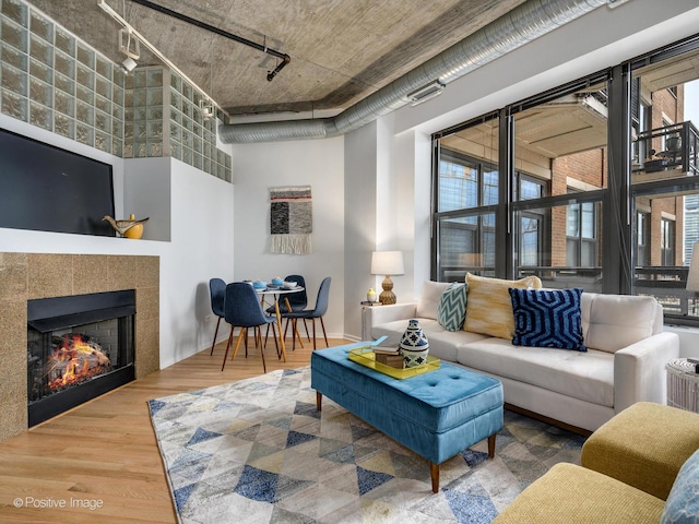 living room featuring a fireplace, wood-type flooring, a towering ceiling, and track lighting