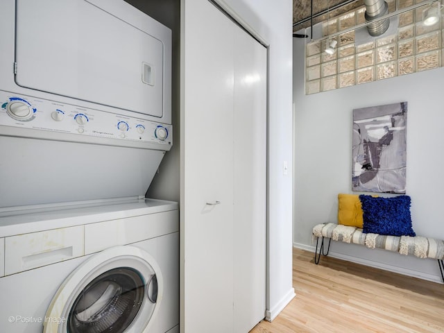 laundry room with stacked washer / dryer and light hardwood / wood-style flooring