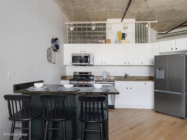 kitchen featuring light hardwood / wood-style floors, a kitchen breakfast bar, white cabinets, and stainless steel appliances