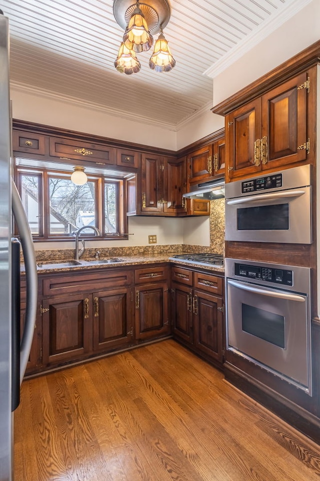 kitchen with sink, crown molding, light hardwood / wood-style flooring, stone counters, and stainless steel appliances