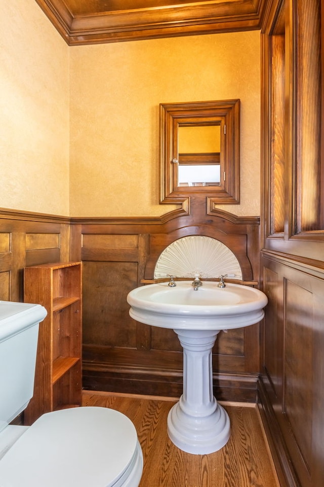 bathroom featuring wood-type flooring, ornamental molding, and toilet